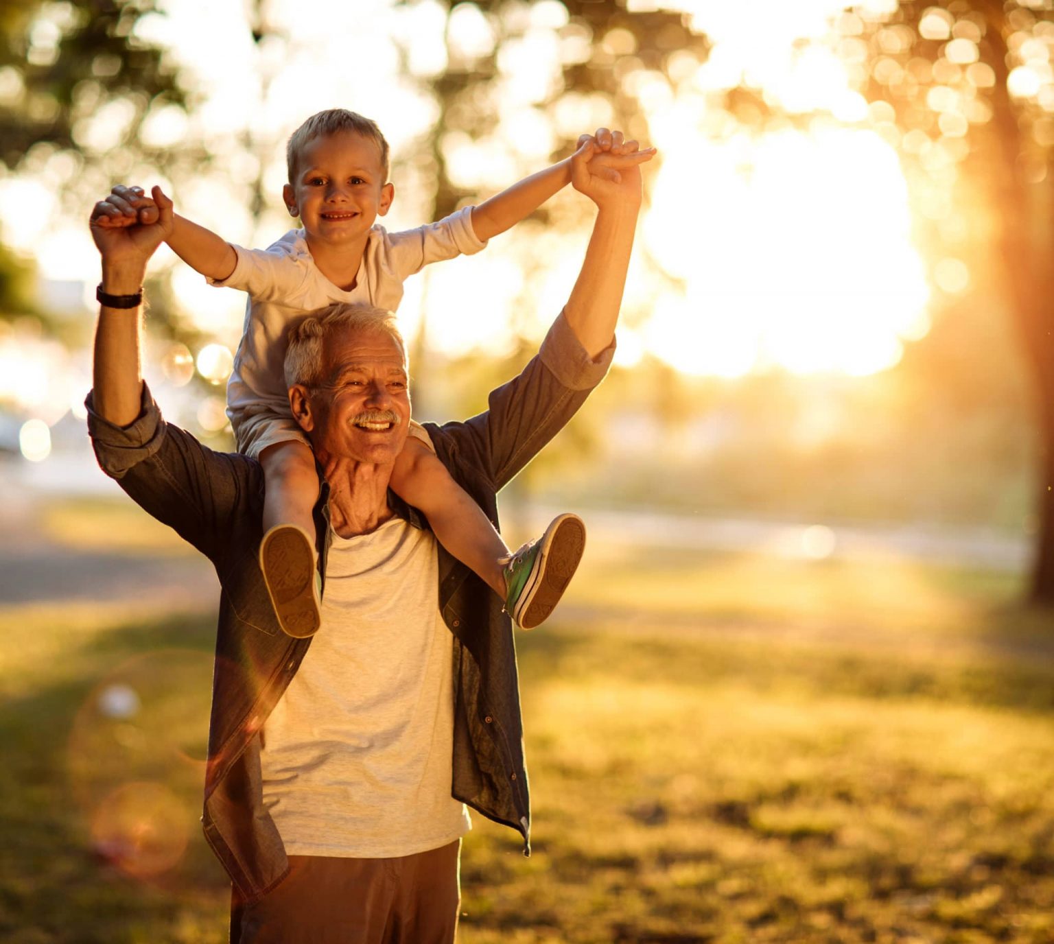 Pediatrics-breathing-disorders-treatment A young boy sits on top of his grandfather's shoulders, both smiling.