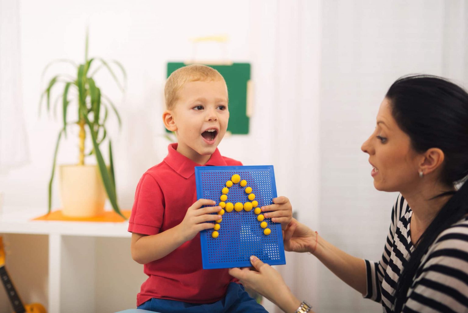 Speech therapy session A young boy holding a sign with an A on it learning how to say A in speech therapy.