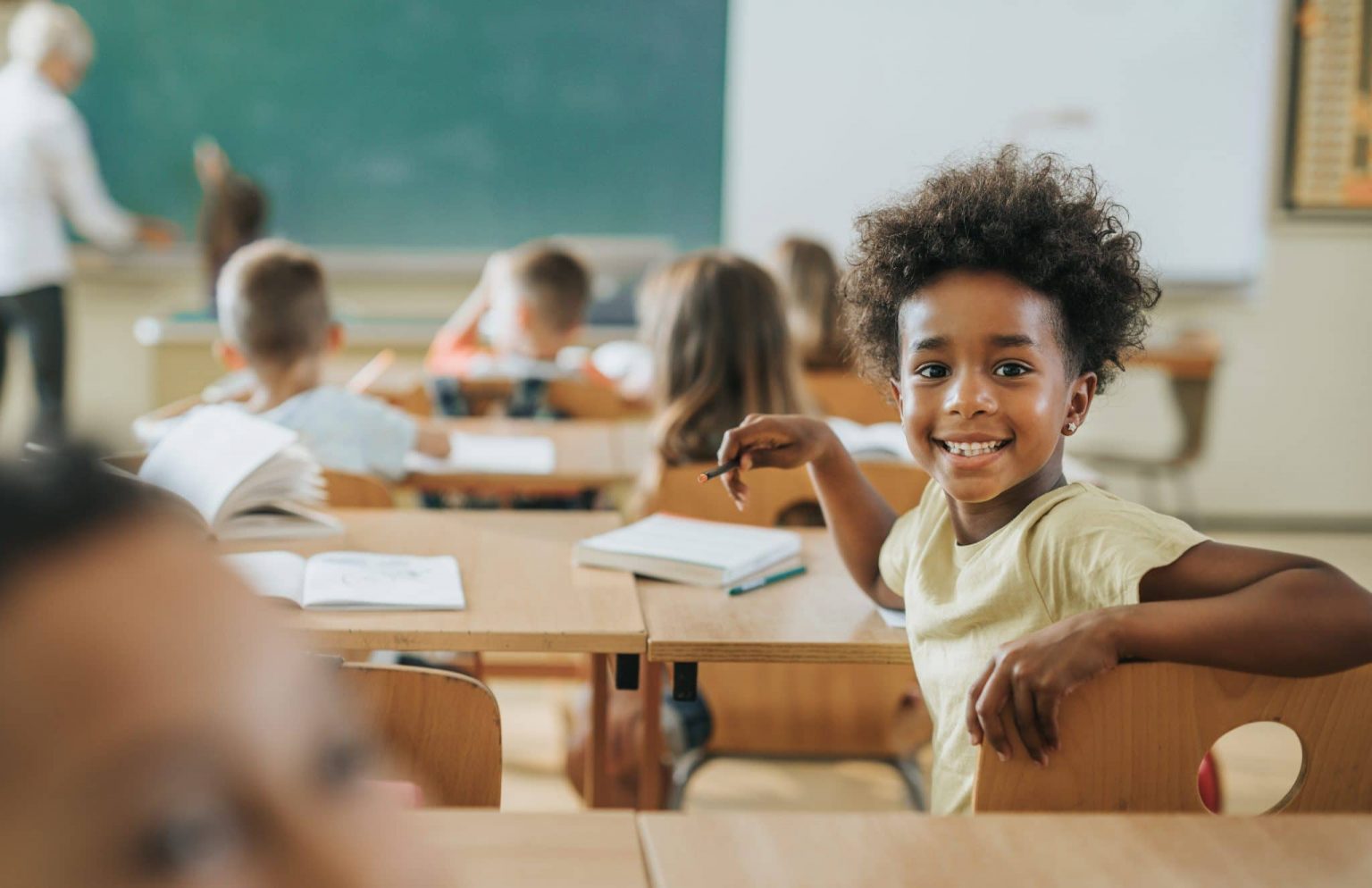 speech-delay-symptoms Happy young girl sitting in class who may be experiencing speech delay.